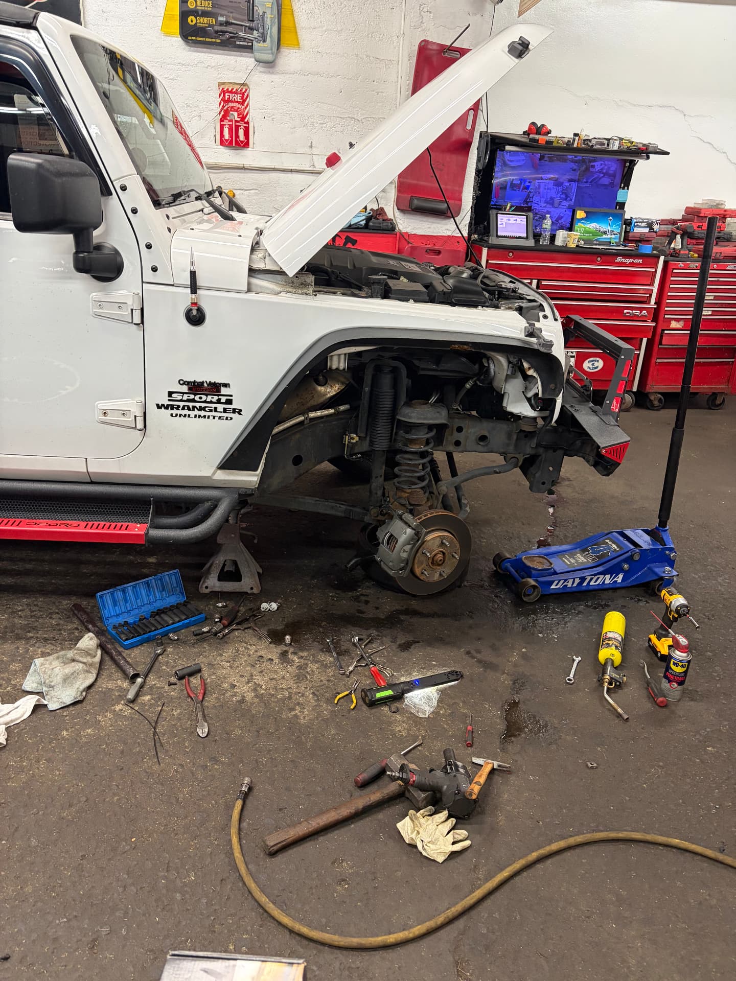 Jeep Wrangler on jack stands with the front fender off and suspension exposed